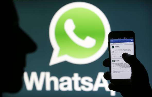 A Whatsapp App logo is seen behind a Samsung Galaxy S4 phone that is logged on to Facebook in the central Bosnian town of Zenica