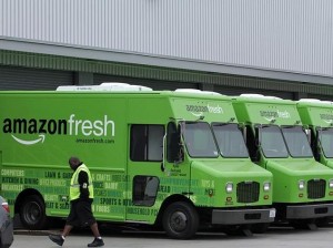 A worker walks past Amazon Fresh delivery vans parked at an Amazon Fresh warehouse in Inglewood