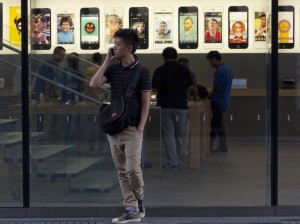 man_using_iphone_in_front_of_apple_store_ap