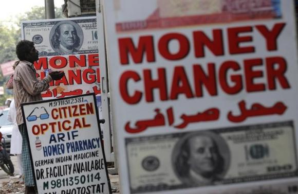 A man begs outside a currency exchange shop in New Delhi