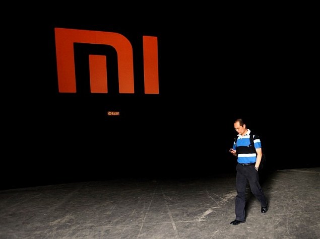 man checks mobile walks past logo xiaomi