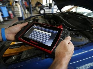 Mechanic John Eppstein uses a basic hand held computer to try and diagnose a vehicle in for repair at his garage in San Diego, California