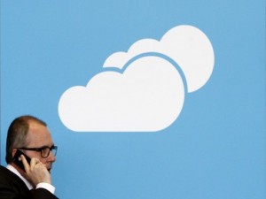 A visitor uses his mobile phone as he walks past the Microsoft booth with a logo for cloud computing software application at the CeBit computer fair in Hanover